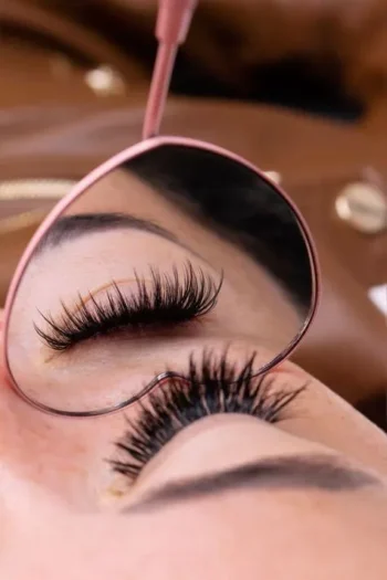 Resultado final de extensiones de pestañas de volumen reflejado en un espejo rosa de corazón.